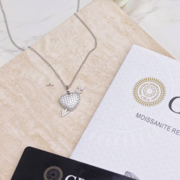 Moissanite arrow in the heart necklace in 925 Sterling Silver on a wooden table